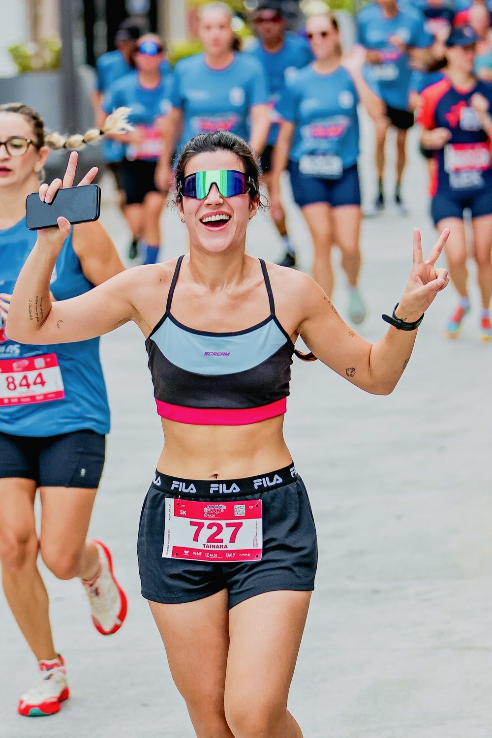 Corredora da Corrida da Tai comemorando ao chegar na linha de chegada